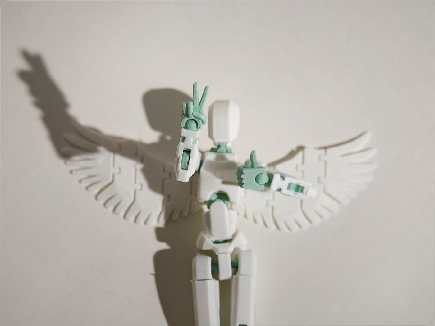 Mint and white winged Dummy 13 guardian figure with a peace-sign pose